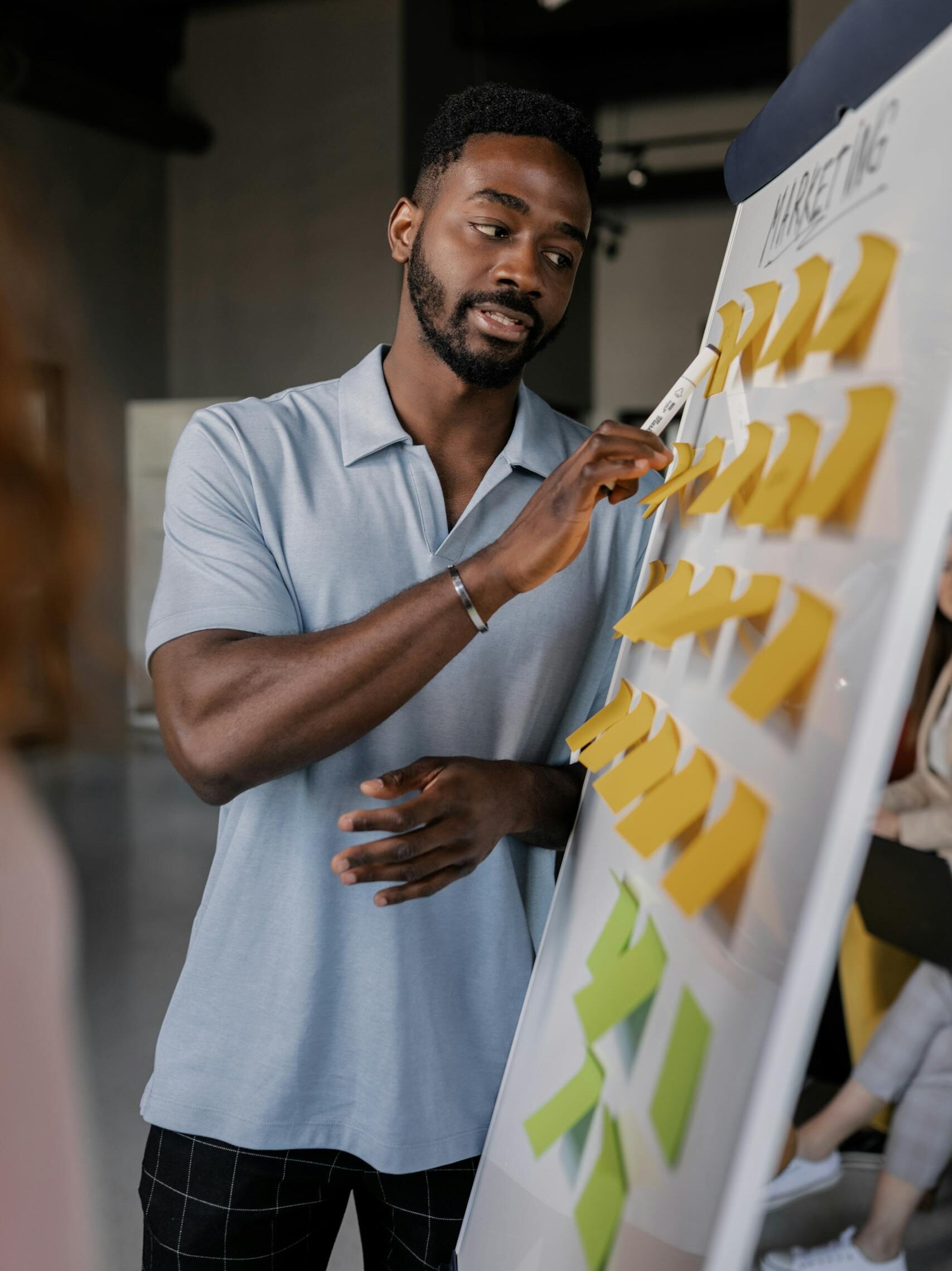Confident African man presenting strategy using sticky notes on whiteboard during a corporate tech training